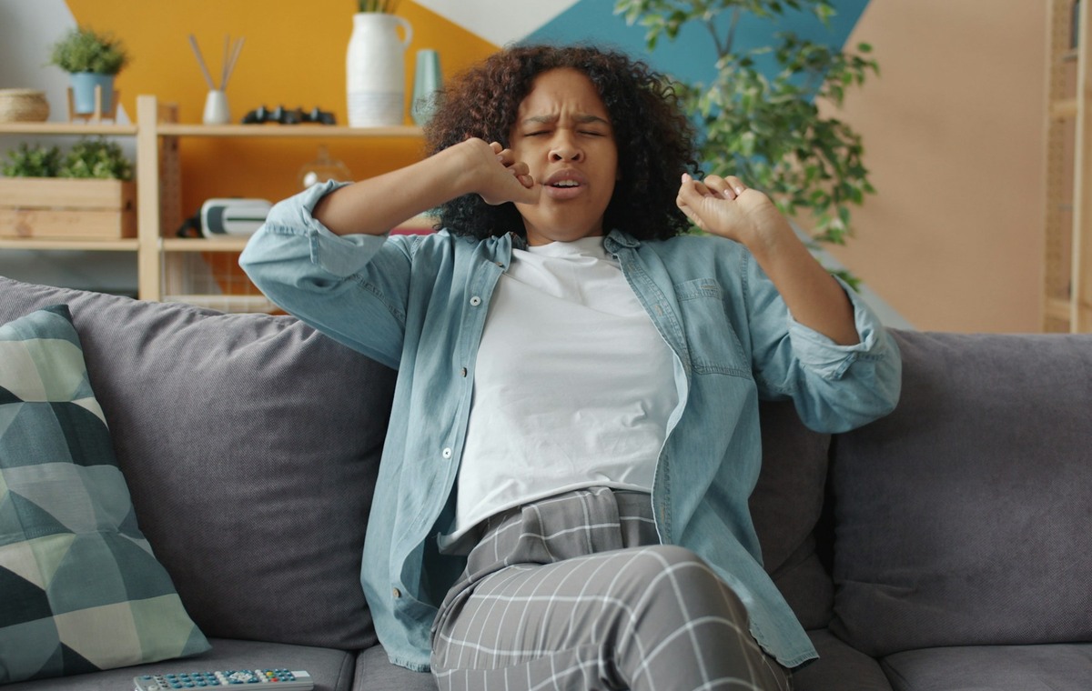 Woman sitting on couch with hands near face